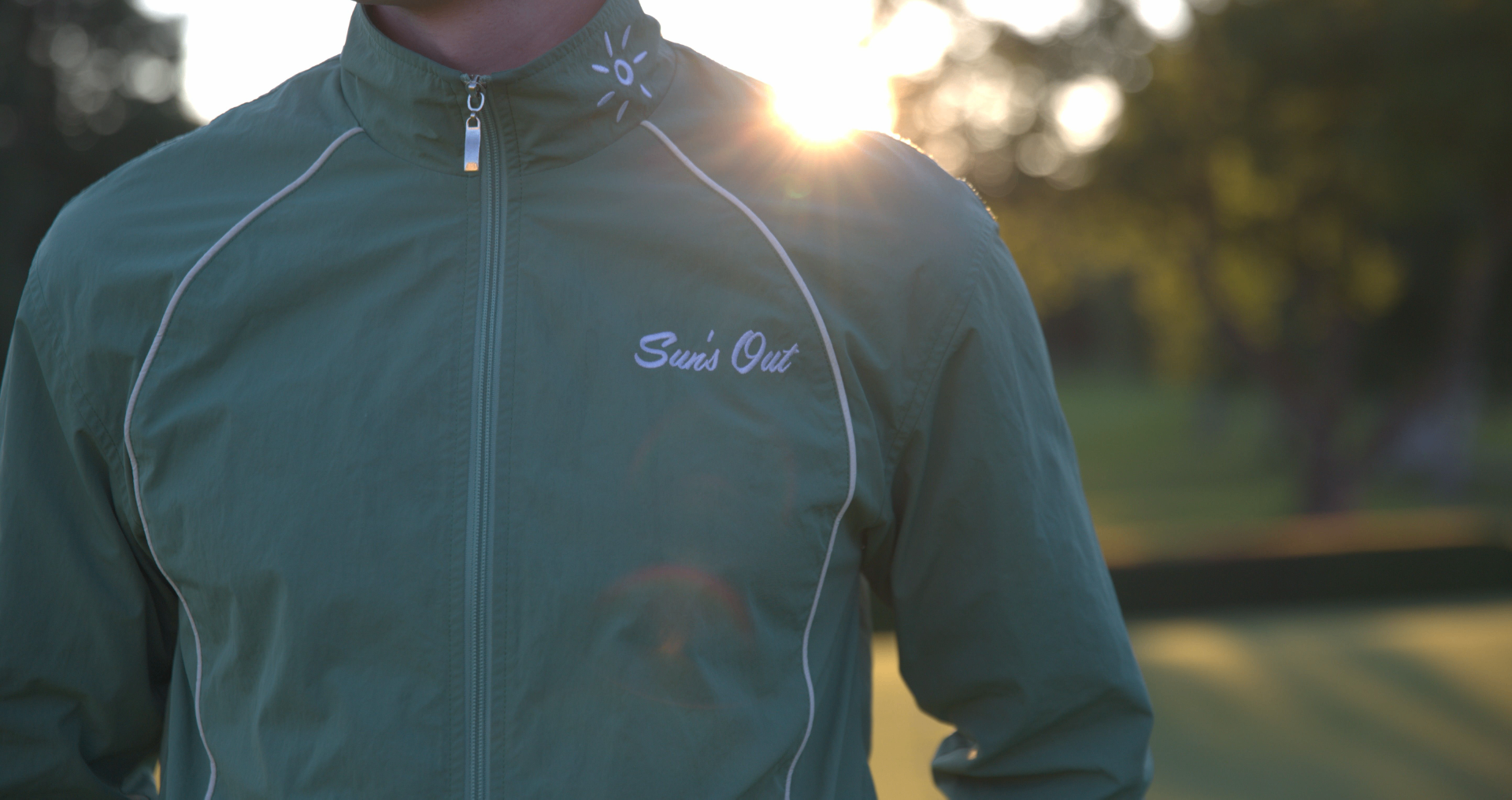 Sun's Out Golf sage green wind jacket at golden hour